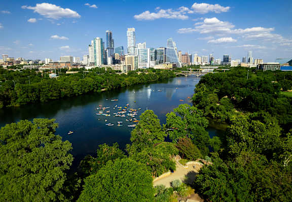 A city skyline is seen from a distance with a body of water in the foreground.