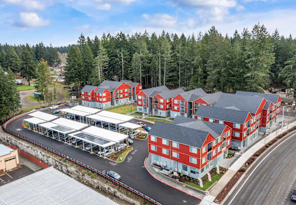 A large red building complex with a parking lot in front.