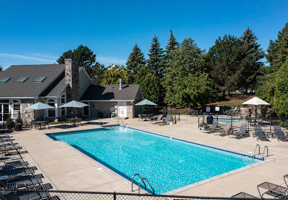 A large swimming pool surrounded by lounge chairs and umbrellas.