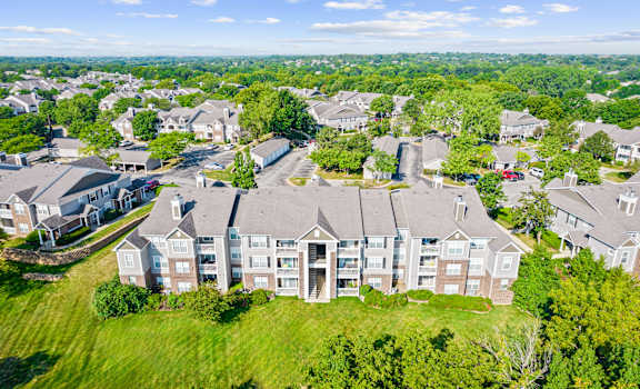 A large, multi-story residential building with a green lawn in front.