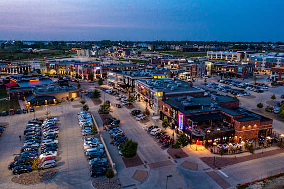 A parking lot with cars and a building with a lit up sign.