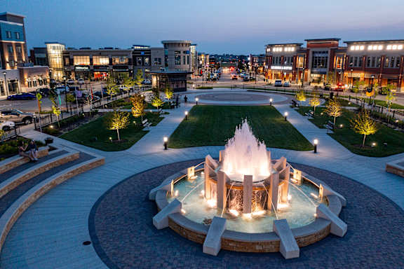 A fountain in the middle of a plaza surrounded by buildings.