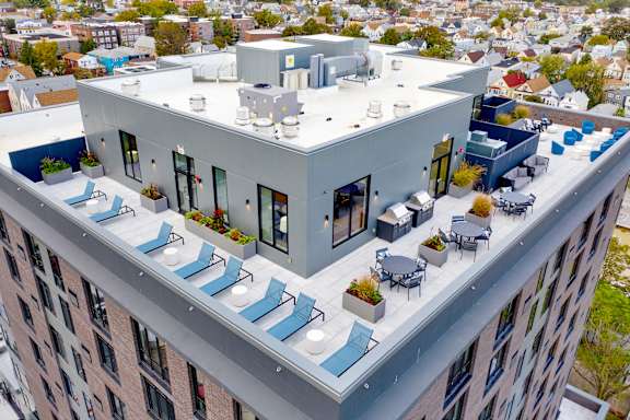 an aerial view of a building with blue lounge chairs and a table and chairs on the roof