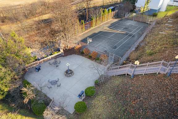 A tennis court surrounded by a fence and trees.