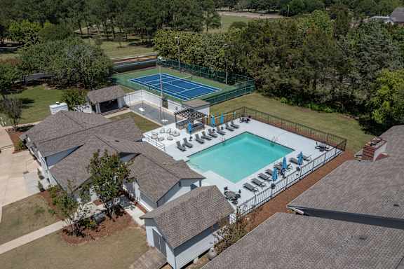 arial view of a house with a pool and tennis court