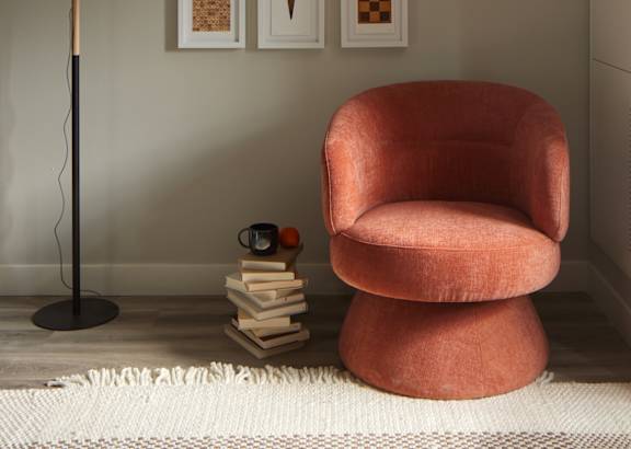 a chair and a lamp in a room with paintings on the wall