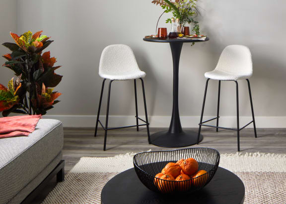 a living room with a table with two chairs and a bowl of fruit