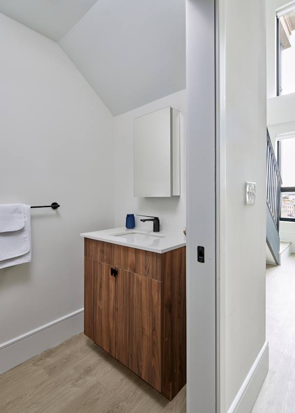 A bathroom with a white sink and a wooden cabinet.