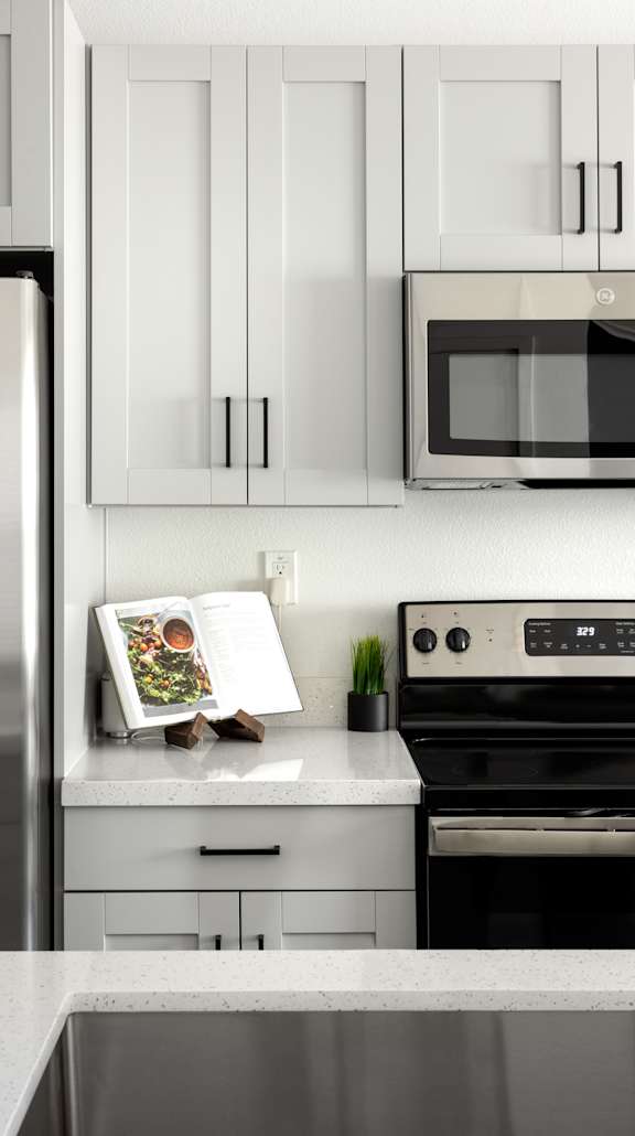 A modern kitchen with a refrigerator, microwave, oven, and cabinets.