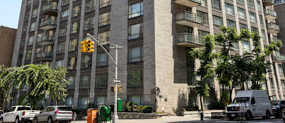 A tall building with many windows is located on a street corner.