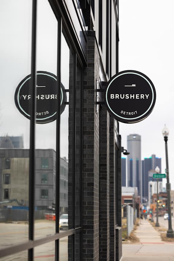 Two signs on a pole that say "Brushery" and "Detroit.".