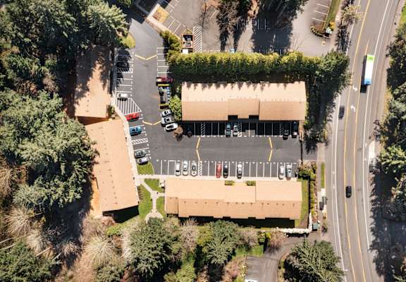 An aerial view of a parking lot with cars and a building.