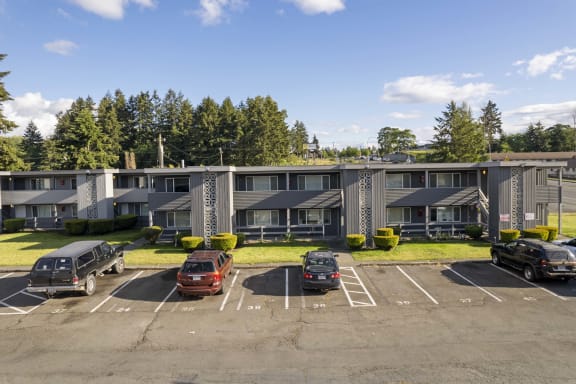 a parking lot with cars in front of an apartment building