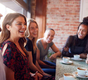 A group of people are sitting around a table with cups of coffee.