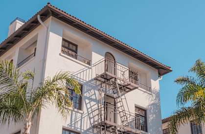 a white building with a fire escape and palm trees