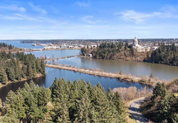 A beautiful landscape with a river, trees, and a building in the distance.