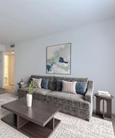 A living room with a grey couch, a coffee table, and a painting on the wall.