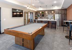 a pool table in a clubhouse with a kitchen and a bar