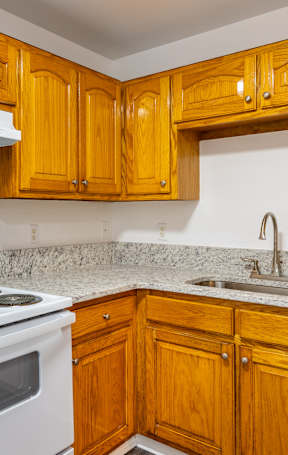 A kitchen with wooden cabinets and a white stove top oven.