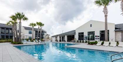 A large swimming pool in front of a building with palm trees.