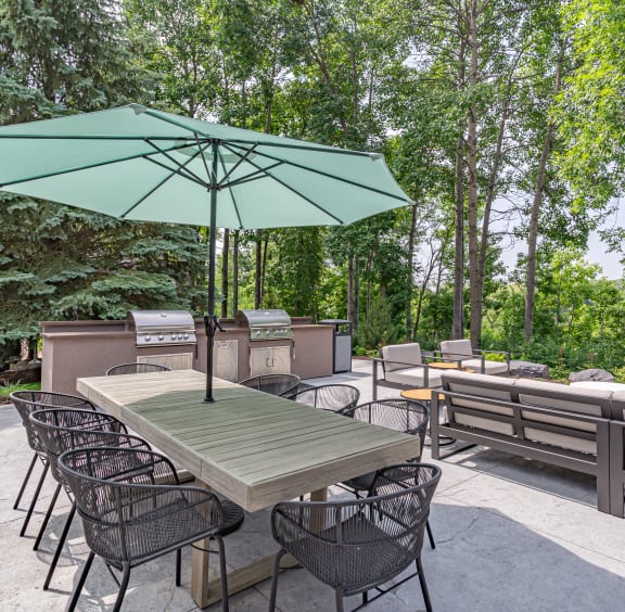 a patio with a table and chairs and a grill