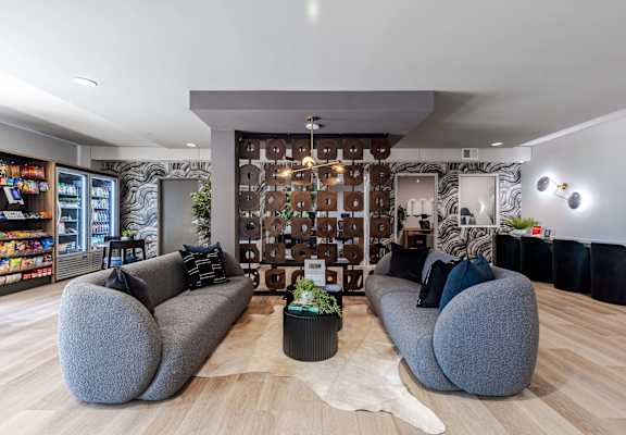 a living room with couches and chairs and a wall covered in tiles