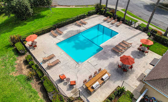 Drone footage of the community pool area showing sun deck with lounge chairs and gas BBQs at Vineyard Terrace Apartments, Napa, CA