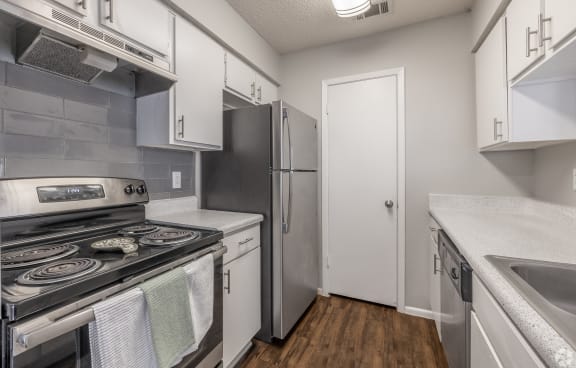 an empty kitchen with stainless steel appliances and white cabinets