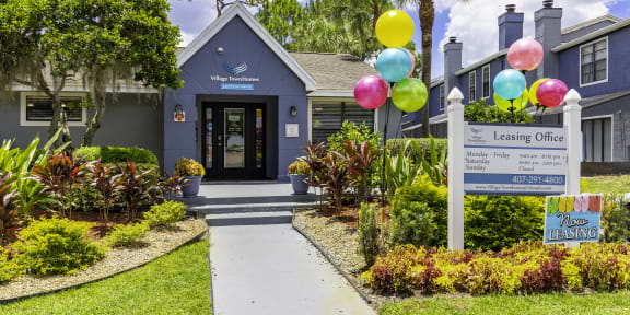 a building with a sign and balloons in front of it