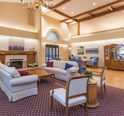 a living room with couches and chairs and a fireplace at River Commons Senior Living, Redding, CA