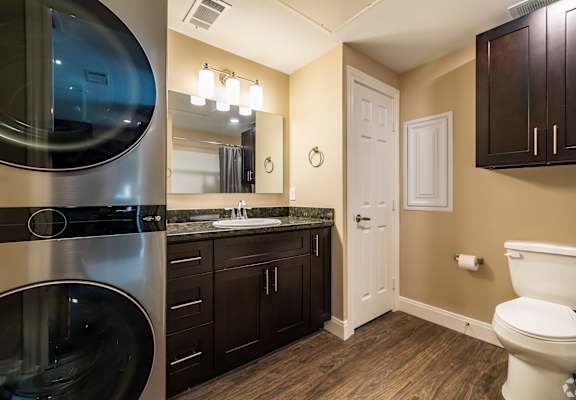 A modern bathroom with a washer and dryer built into the cabinetry.
