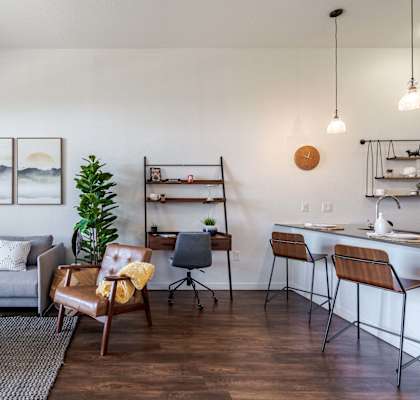 a living room with a couch and a table and a kitchen with a desk