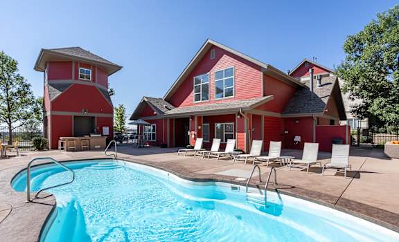 a swimming pool in front of a red house with a pool at Stetson Meadows Apartments, Colorado Springs, CO, 80922