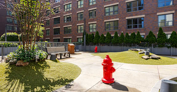 a red fire hydrant on a sidewalk in front of a brick building