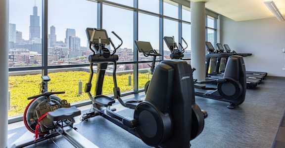 a gym with cardio machines and a view of the city
