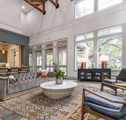 a living room with couches and chairs and large windows