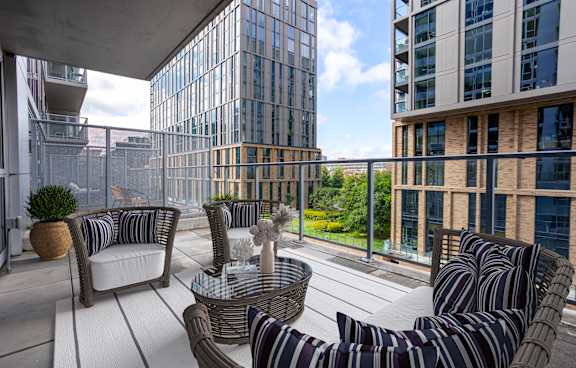 A patio with striped couches and a table with a vase of flowers on it.