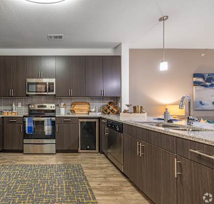 A modern kitchen with a refrigerator, oven, and microwave.