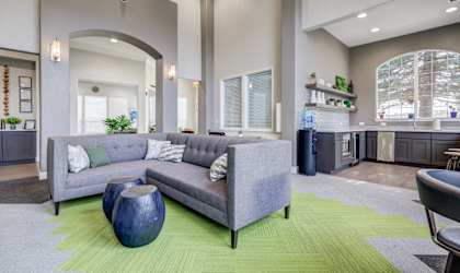 A living room with a grey couch and a blue vase.