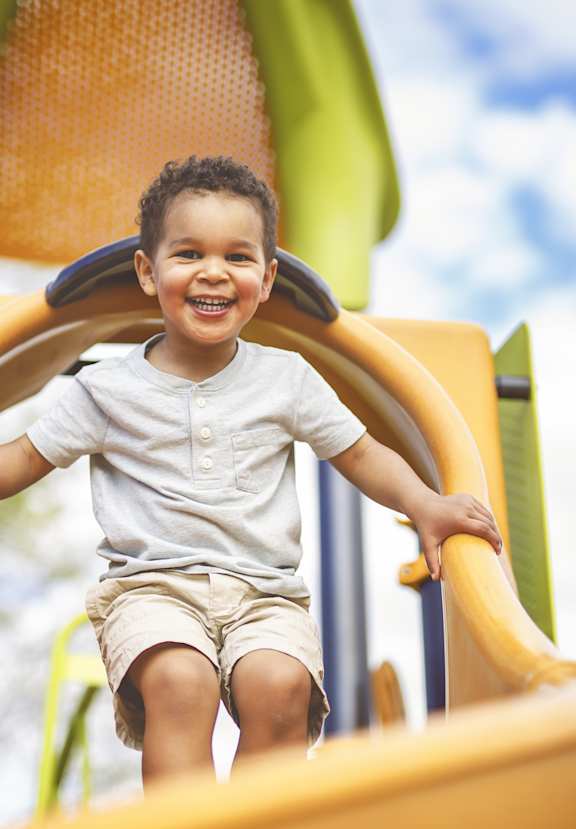 A child is playing on a yellow slide.