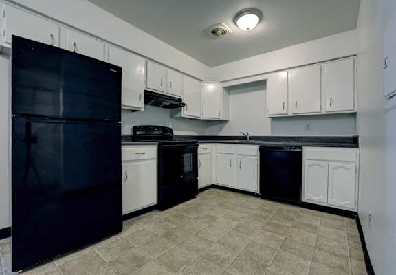 A kitchen with black appliances and white cabinets.