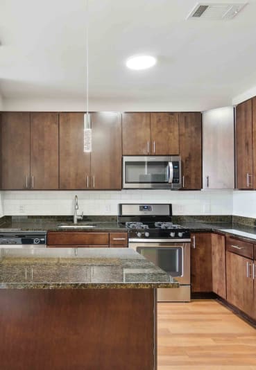 a kitchen with dark wood cabinets and an island with granite countertops at West 130, New York