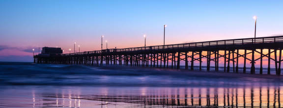 pier on the beach at sunset with the ocean