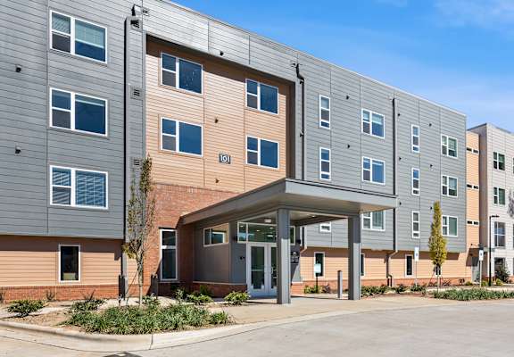 A parking lot in front of a multi-story apartment building.