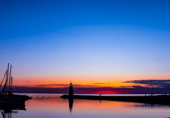 a lighthouse silhouetted against a colorful sunset