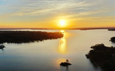 an aerial view of the sun setting over a body of water