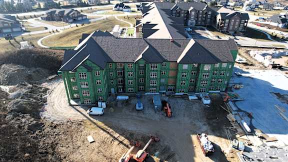 A green building under construction with a lot of dirt around it.