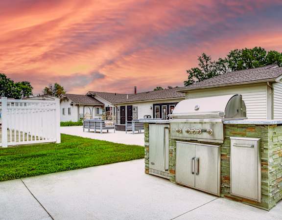 A backyard with a white fence and a stone and wood outdoor kitchen.