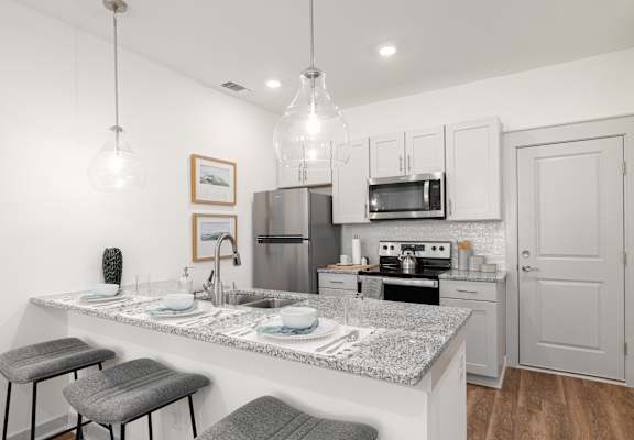 A kitchen with a granite countertop and stools.