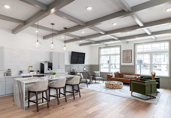 A modern kitchen with a bar area and a living room with a couch. at Allier Port Wentworth Apartments, Port Wentworth 31407